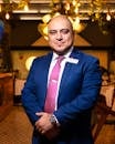 Portrait of a confident businessman in a restaurant, elegantly dressed in a blue suit and pink tie.