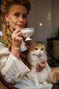 An elegant woman enjoying tea with her fluffy Scottish Fold cat.